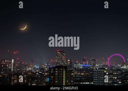 Londra, Regno Unito. 23rd febbraio 2023. UK Weather: La moonset sulla città vede un 17,9% Waxing Crescent moon impostazione sopra la città durante la tarda sera muoversi in una direzione nord-nord ovest. Credit: Guy Corbishley/Alamy Live News Foto Stock