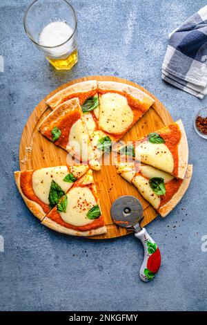 Fette di pizza appena cotte con taglierina sul tavolo Foto Stock