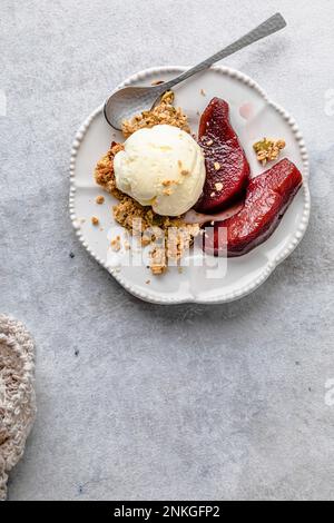Piatto di pere al vino rosso con gelato e granola Foto Stock