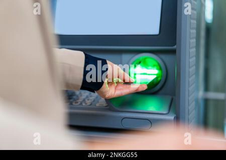 Mano di businesswoman che inserisce la carta di credito in ATM Foto Stock