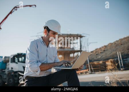 Architetto maturo che lavora su un notebook nell'area delle costruzioni Foto Stock