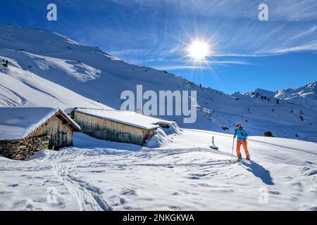 Austria, Tirolo, Sole splendente sulle sciatrici che passano rifugi appartati nelle Alpi Tux Foto Stock
