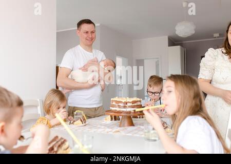 Padre che porta figlio con i bambini che mangiano la torta seduto al tavolo Foto Stock