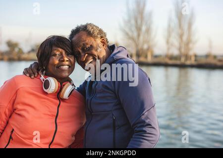 Felice coppia anziana di fronte al lago al tramonto Foto Stock