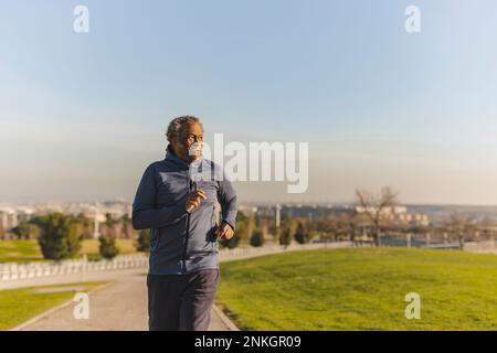 Uomo anziano che corre nel parco nelle giornate di sole Foto Stock