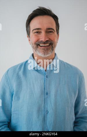 Uomo felice e maturo che indossa una camicia su sfondo bianco Foto Stock