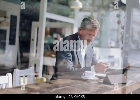 Uomo d'affari che fa colazione e usa un tablet PC al bar Foto Stock