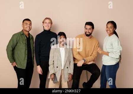 Sorridenti colleghi d'affari multirazziali in posa su sfondo beige Foto Stock