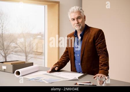 Designer di moda fiducioso in piedi alla scrivania in studio Foto Stock