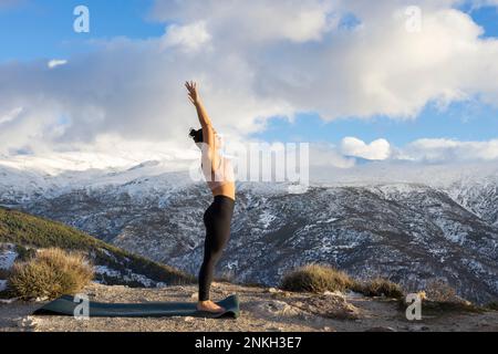 Donna che fa esercizi di stretching in montagna Foto Stock