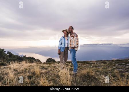 Coppia matura in piedi insieme sulla montagna al tramonto Foto Stock