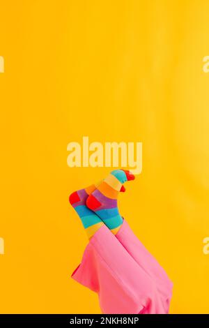 Piedi di donna con calzini colorati su sfondo giallo Foto Stock