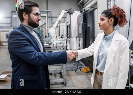 Uomo d'affari sorridente che scuote le mani con un collega dell'industria Foto Stock