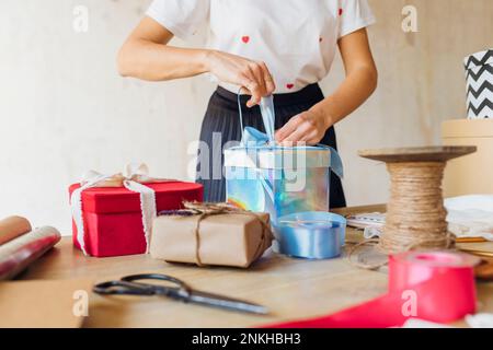 Donna legatura nastro sulla scatola regalo alla scrivania Foto Stock