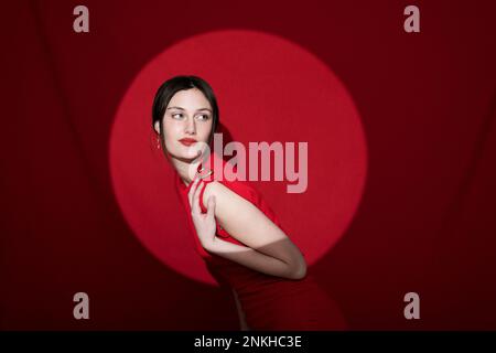 Bella giovane donna che posa su sfondo rosso Foto Stock