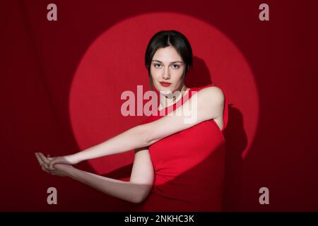Giovane donna fiduciosa che posa su sfondo rosso Foto Stock