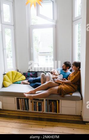 Padre e madre seduti con la figlia sul sedile di casa Foto Stock