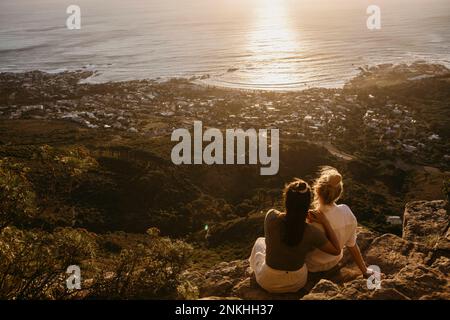 Amici che ammirano il mare seduto sulla roccia a Signal Hill Foto Stock