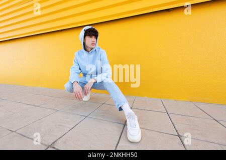 Giovane uomo che indossa una camicia con cappuccio che squattera sul sentiero Foto Stock