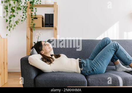 Giovane donna rilassante sul divano di casa Foto Stock