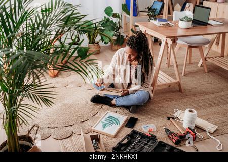 Donna matura che fa cornici fai da te a casa Foto Stock