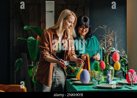 Donna felice con tavolo madre impostazione per la cena di Pasqua a casa Foto Stock