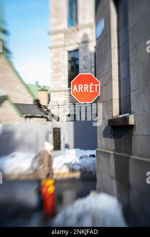 Immagine invernale a fuoco selettivo di un segnale di stop nella sezione storica di Quebec City con la parola stop scritta in francese ("arret") Foto Stock