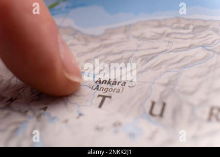 Primo piano con un dito che punta ad Ankara, Turchia, su una mappa colorata dettagliata con messa a fuoco selettiva, profondità di campo ridotta, sfocatura dello sfondo Foto Stock