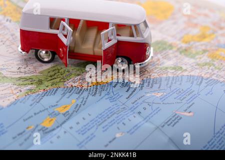 OGDEN, UTAH USA - FEBBRAIO 10 2023 Un pulmino VW rosso e bianco in miniatura con le sue porte si apre su una mappa della costa californiana con focus selettivo su Los Foto Stock