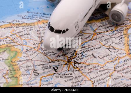 Primo piano di un aereo passeggeri in miniatura su una mappa colorata che evidenzia Madrid, Spagna attraverso la messa a fuoco selettiva, sfocatura dello sfondo Foto Stock