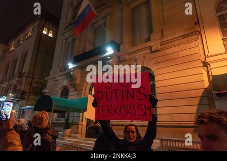 NEW YORK, NEW YORK - 23 FEBBRAIO: Una donna ha in mano un cartello "STOP PUTINS TERRORISM" alla vigilia di un anno di invasione russa al di fuori dell'edificio del consolato russo nell'Upper East Side di Manhattan il 23 febbraio 2023 a New York City. Ucraini e russi parlano contro la guerra, Putin e piangono le vittime dell'invasione. Foto Stock