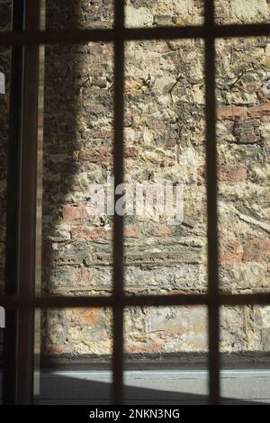 Un colpo verticale di muro visto attraverso barre metalliche Foto Stock