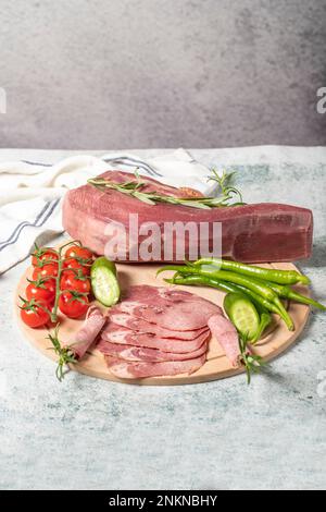 Lingua di manzo affumicata. Linguetta di vitello affumicata tagliata su tagliere in legno. Deliziosa carne affumicata. Nome locale fumo dana dil Foto Stock