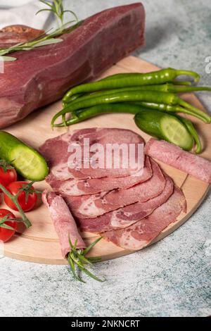 Lingua di manzo affumicata. Linguetta di vitello affumicata tagliata su tagliere in legno. Deliziosa carne affumicata. Nome locale fumo dana dil Foto Stock