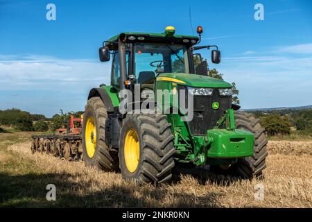 Grande trattore agricolo John Deere a 7280R file, verde brillante, con pneumatici grandi e erpice a dischi parcheggiato a Leicestershire Field, Inghilterra, Regno Unito Foto Stock