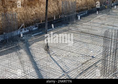 Pompa per calcestruzzo che lavora su fondazioni rinforzate in un cantiere di grandi dimensioni Foto Stock