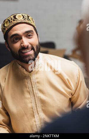 Uomo musulmano sorridente guardando la moglie sfocata a casa, immagine di scorta Foto Stock