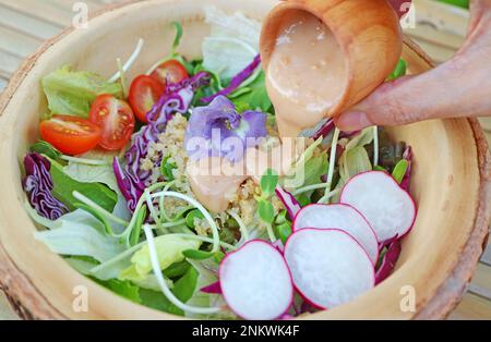 Primo piano di un delizioso condimento a base di insalata aggiunto all'insalata di quinoa e verdure Foto Stock