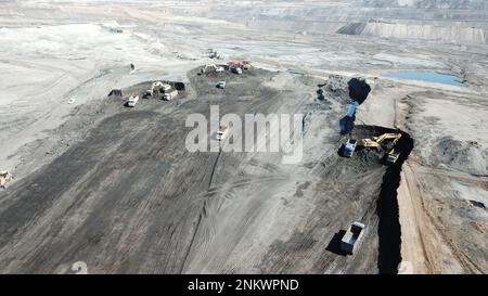 Escavatori in funzione. Caricamento di autocarri in un enorme sito minerario. Foto Stock