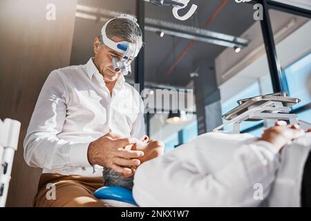 Esame oculare, torcia ottica e medico con paziente anziano per test oculistico. Benessere, assistenza sanitaria e consulenza ospedaliera di un medico Foto Stock