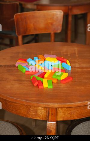 La torre in rovina del gioco Jenga. Blocchi colorati sparsi sul tavolo. Distruzione, caduta, perdita Foto Stock