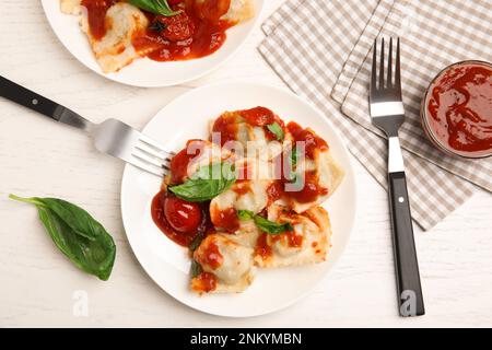 Gustosi ravioli con salsa di pomodoro serviti su un tavolo di legno bianco, piatto Foto Stock