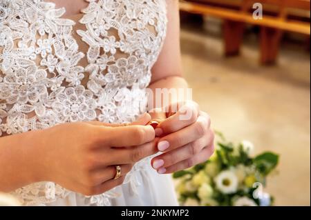 mani, anelli di nozze e voti di matrimonio la sposa tiene e mette un anello di nozze sul dito dello sposo Foto Stock