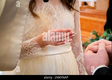 mani, anelli di nozze e voti di matrimonio la sposa tiene e mette un anello di nozze sul dito dello sposo Foto Stock