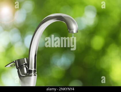 Goccia d'acqua che scorre dal rubinetto all'aperto nelle giornate di sole, effetto bokeh Foto Stock