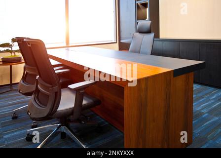 Una sala conferenze professionale con un tavolo in legno e quattro sedie in pelle nera posizionate di fronte a una grande finestra Foto Stock