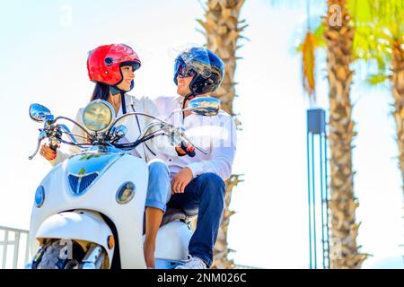 Bella giovane coppia innamorata di andare in scooter in una bella spiaggia di mare in giornata Foto Stock