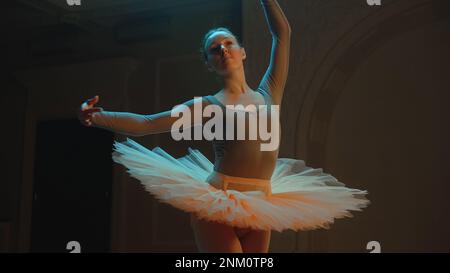 Ripresa cinematografica di una bella ballerina classica femminile in abito tutu bianco che balla nella lobby dell'opera e si prepara ad iniziare lo spettacolo. Coreografia prima dell'inizio di uno spettacolo. Balletto classico art. Foto Stock