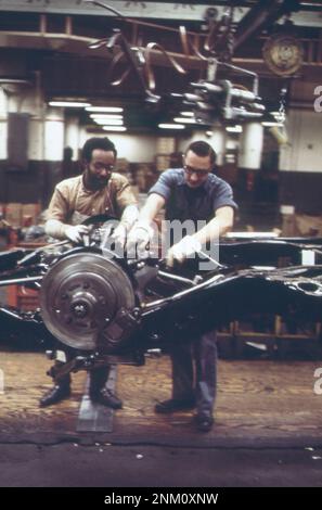 1970s America: Sulla linea di montaggio Cadillac--fissaggio dell'assale al telaio ca. 1973 Foto Stock