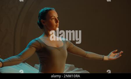 Ripresa cinematografica di una bella ballerina classica femminile in abito tutu bianco che balla sul palco del teatro e si prepara ad iniziare lo spettacolo. Coreografia prima dell'inizio dello spettacolo. Balletto classico art. Foto Stock